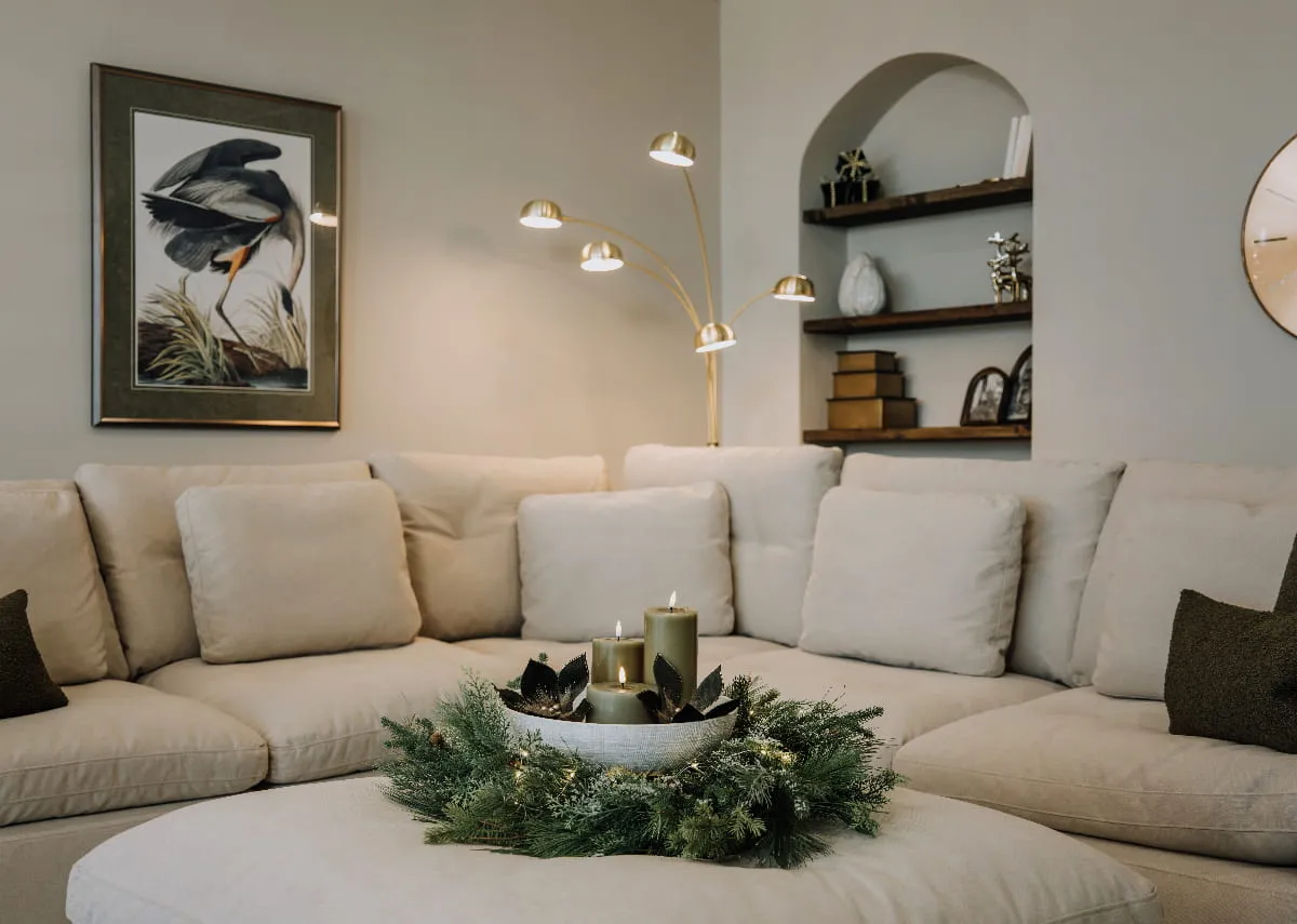 A lifestyle image of the Cozy sofa with footstool with a frosted wreath with bowl of green candles