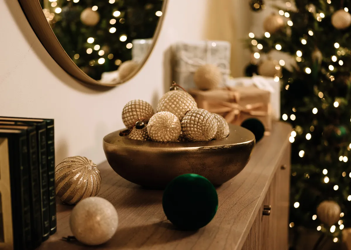 A lifestyle image of the gold Rockin bauble with Mid winter baubles on a sherwood branch with yeloow gold theme setting