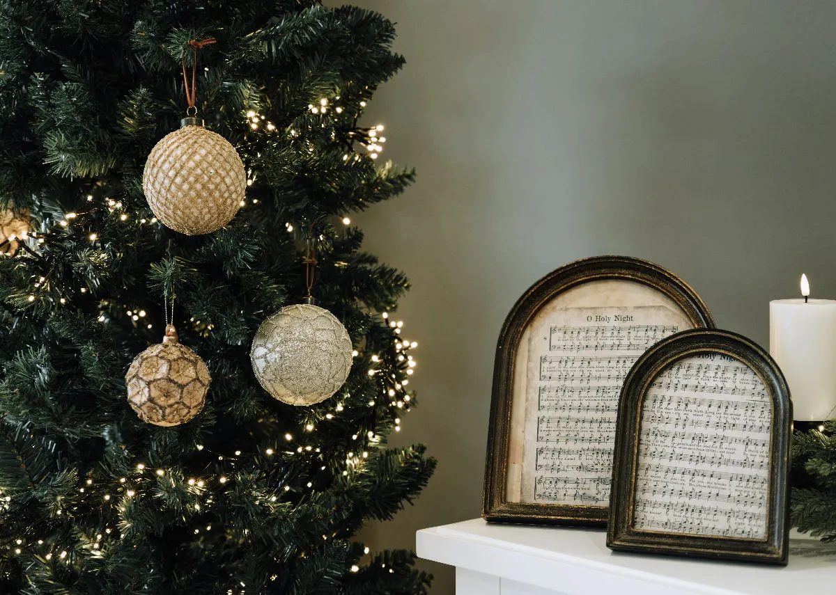 A lifestyle image of the Noble tree with a selection of gold baubles including the Jingle Bell Rock bauble.