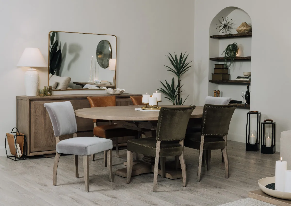 A lifestyle image of the Gold Coast Round dining table with Athy chairs in grey green and leather