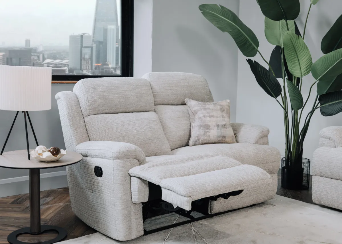 A lifestyle image of the Embrace silver 2 seater reclined with starlette lamp on blanco side table.