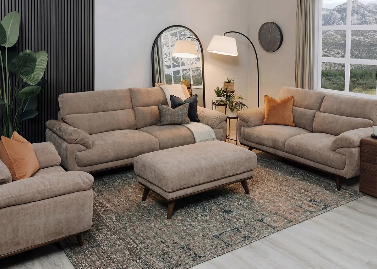 A lifestyle image of the Pippa beige fabric sofa range with matching footstool on a Maxima rug with Chrisley mirror.