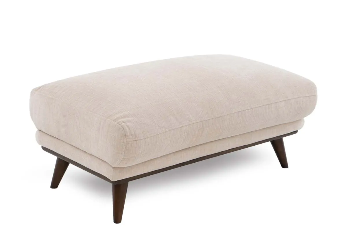 A cream large footstool from EZ Livings Pippa Range. Angled view of plump cushion seat and dark wood legs.