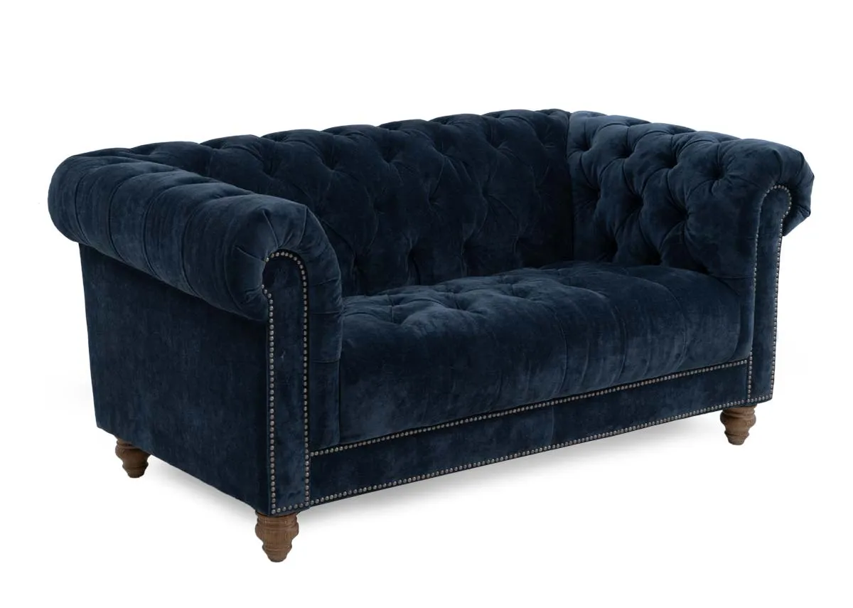 A 2 seater roll back sofa from EZ Livings Adare range. Angled view of midnight blue fabric with tufted button finish.