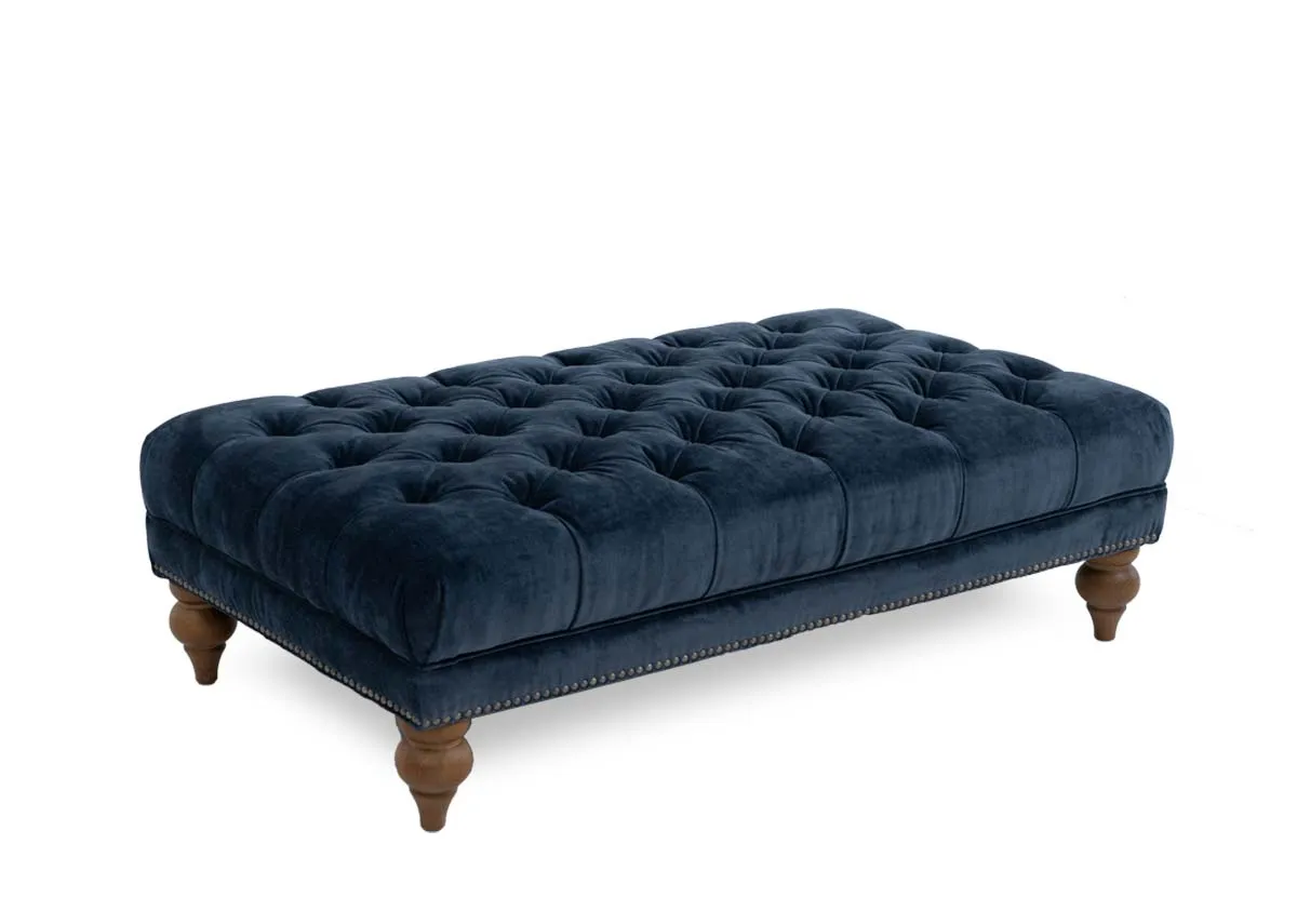 A blue fabric rectangular footstool from EZ Livings Adare range. Angled view of tufted button detail on top
