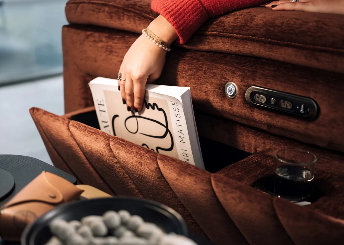 A lifestyle image of the Paige recliner with a conceled side opening for storage and a drinks holder.