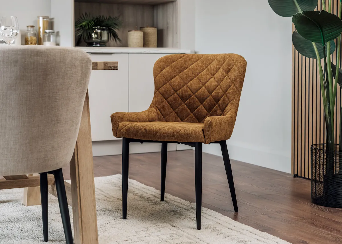 A lifestyle image of the Ottowa Signature gold fabric dining chair with the Albany dining table.