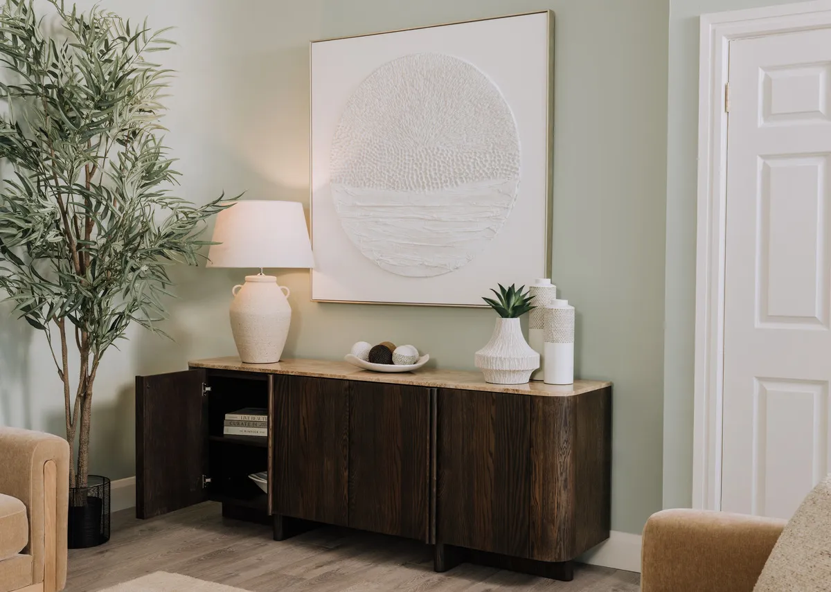 A lifestyle image of the Brosna lamp with a slection of vases on the Ritz sideboard with Pathways canvas.