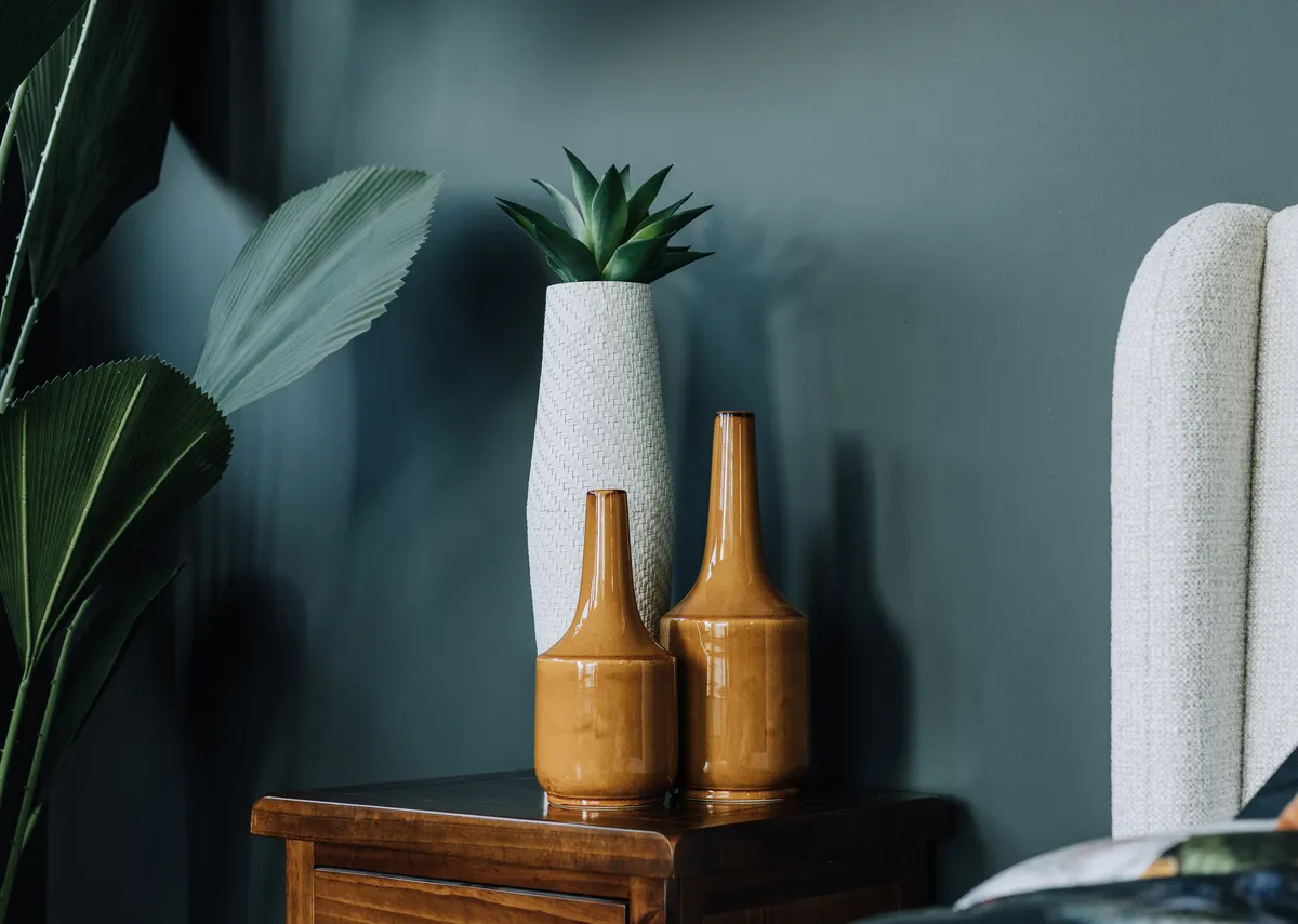 A lifestyle image of the Leya locker with Jade vase and 2 mustard vases by a bed