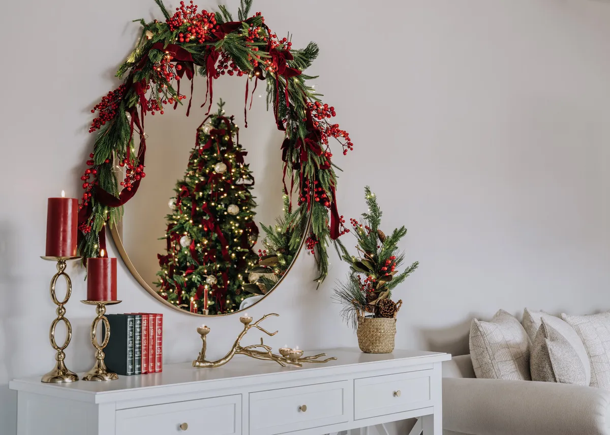 A lifestyle image of the Hampton console with round elling with Ember berry garland and tree.