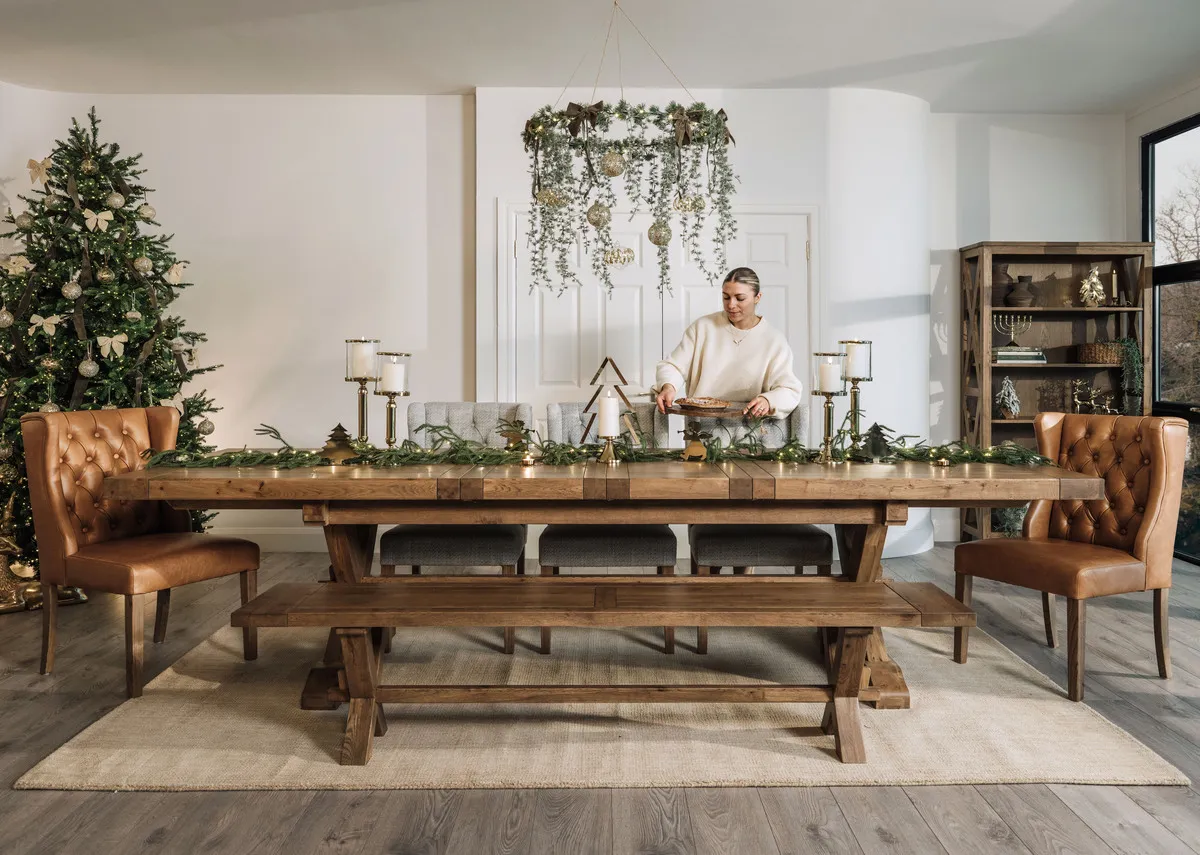 A lifestyle image of the Naxos table with gold candleholder and cream bows on the Rockefeller tree