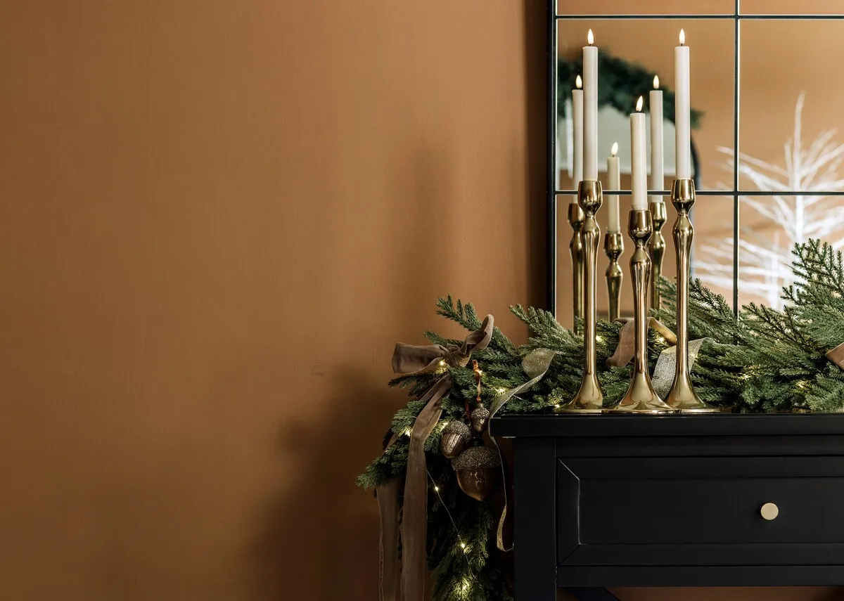 A lifestyle image of the bVintage Taupe roll with a garland and 3 gold candle holders.