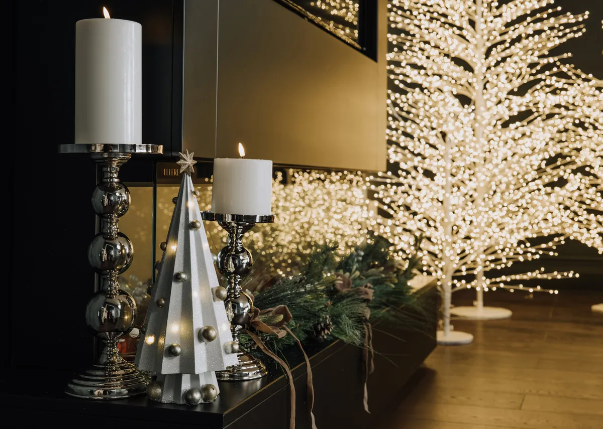 A lifestyle image of the Steel candle holders with led and rudy white trees.
