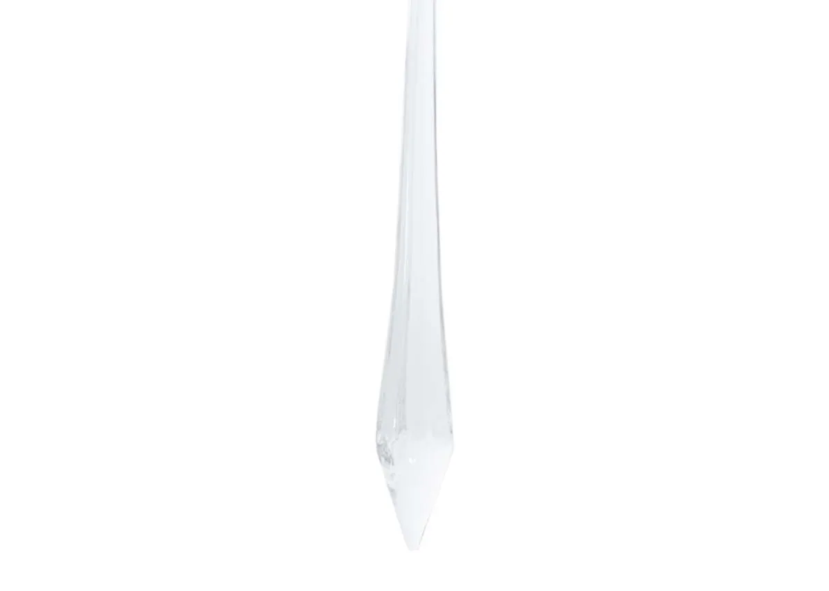 A close up of the tapered pointed tip of a clear large glass drop icicle ornament highlighting its translucent quality.