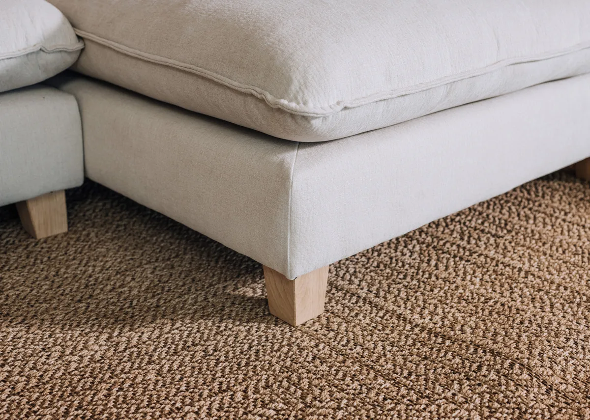 A lifestyle image of the Kenzy rug with a closeup on the fabric with the Howth sofa.