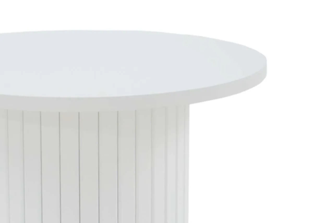 A close up view of the smooth round white table top and the upper part of its fluted cylindrical base showing texture.
