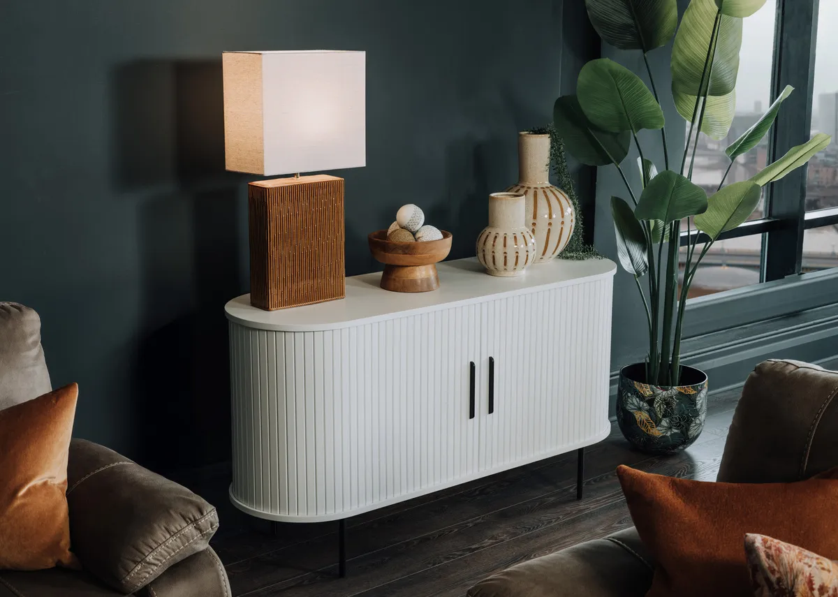 A lifetsyle image of the Nola white sideboard with dee table lamp and Nikita sofa range.