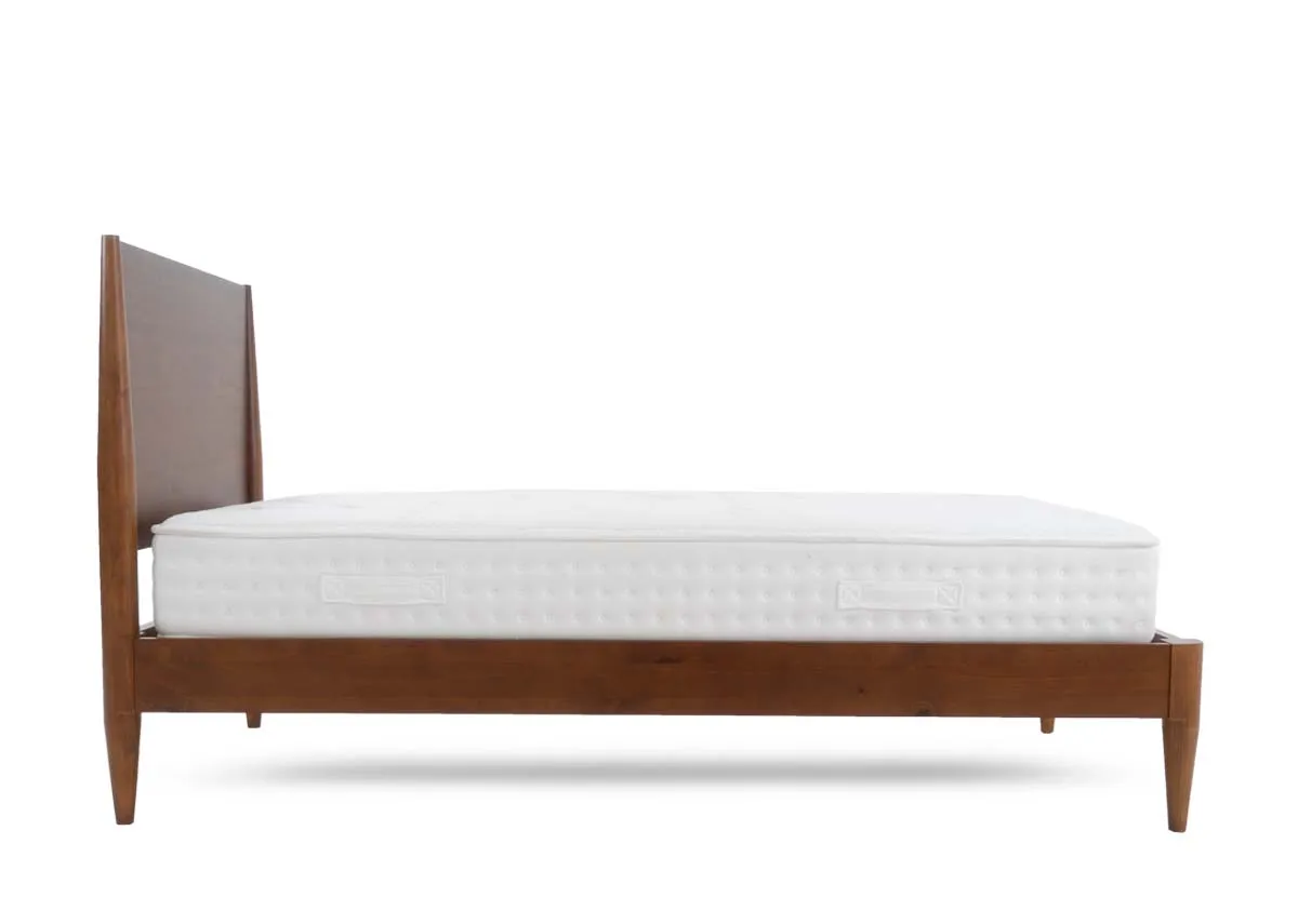 A wooden bed frame with a tall headboard and tapered legs holding a white quilted mattress with a smooth top surface.