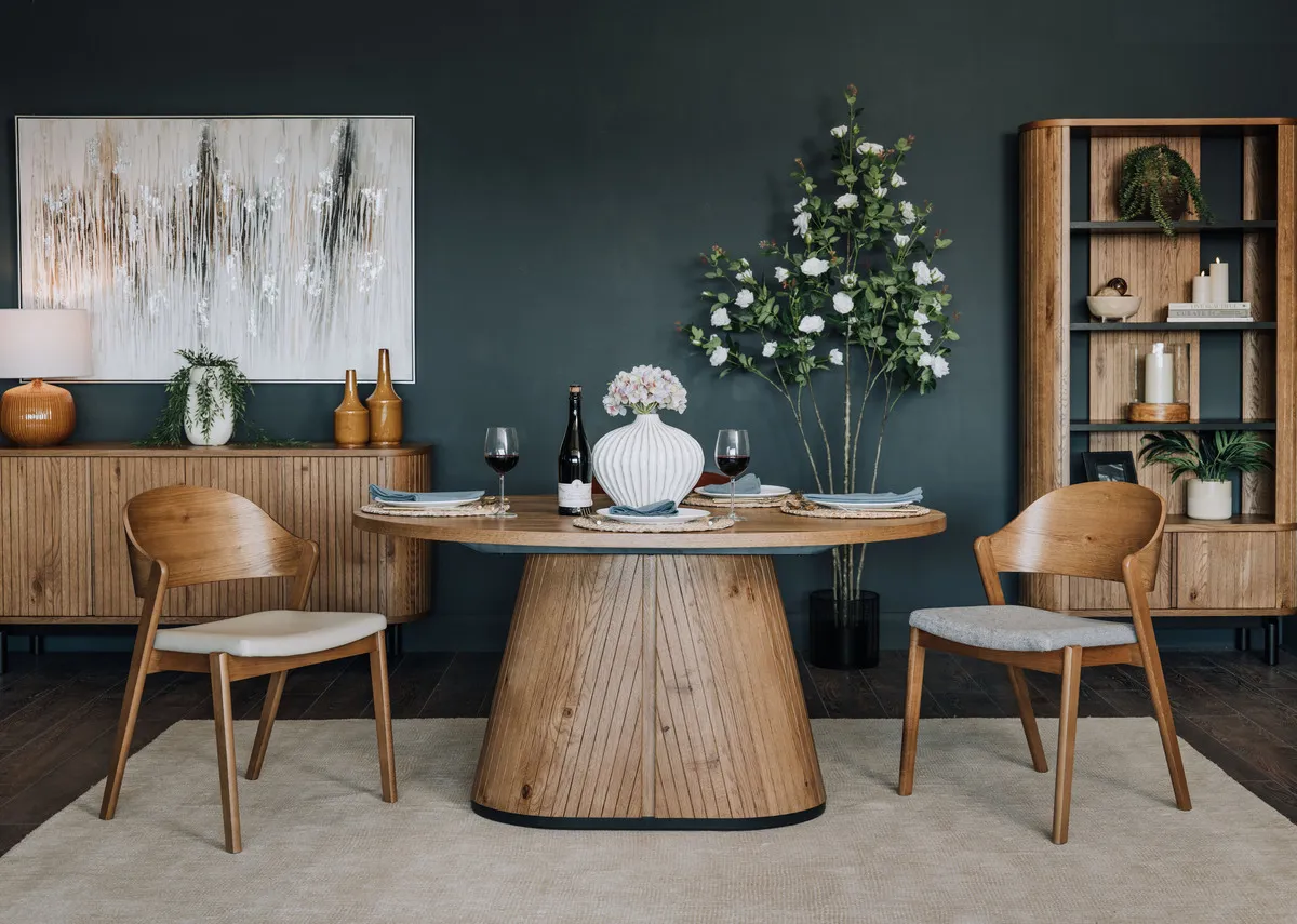 A lifestyle image of the Lorito vase on the Vega dining table with bookcase and sideboard and rustic chairs.