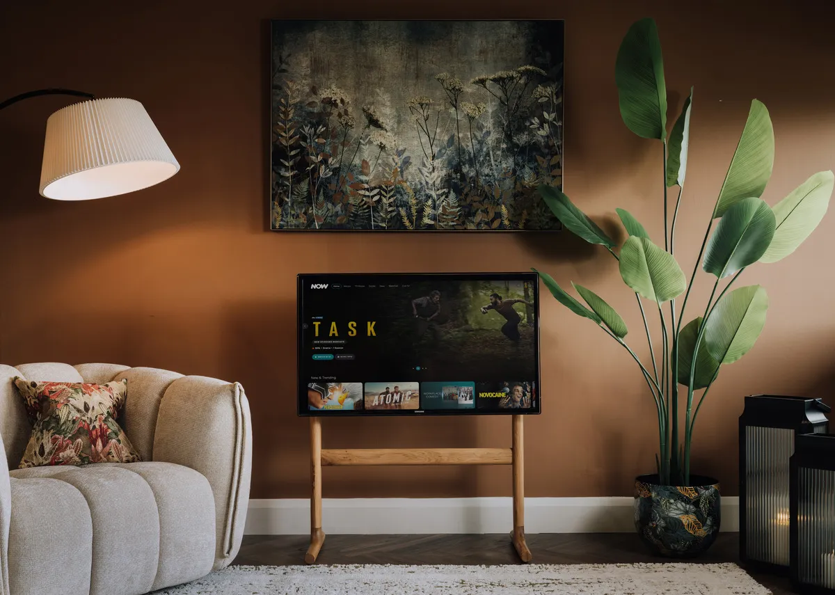A lifestyle image of the leo Stand with a tv and fanciful canvas