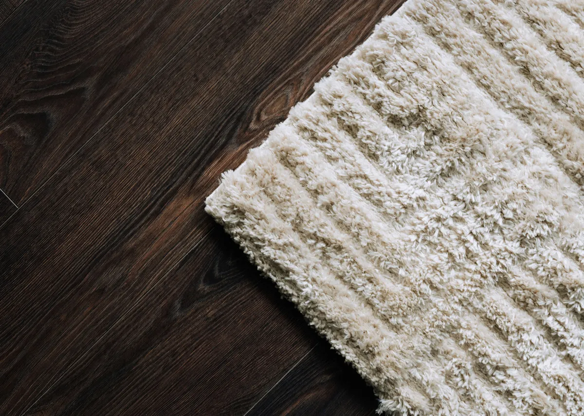 A lifestyle image of the Moasic rug on a dark wood floor.