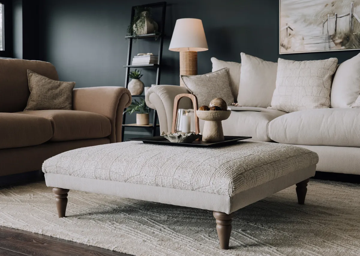 A lifestyle image of the Paloma footstool with a selection of accessories