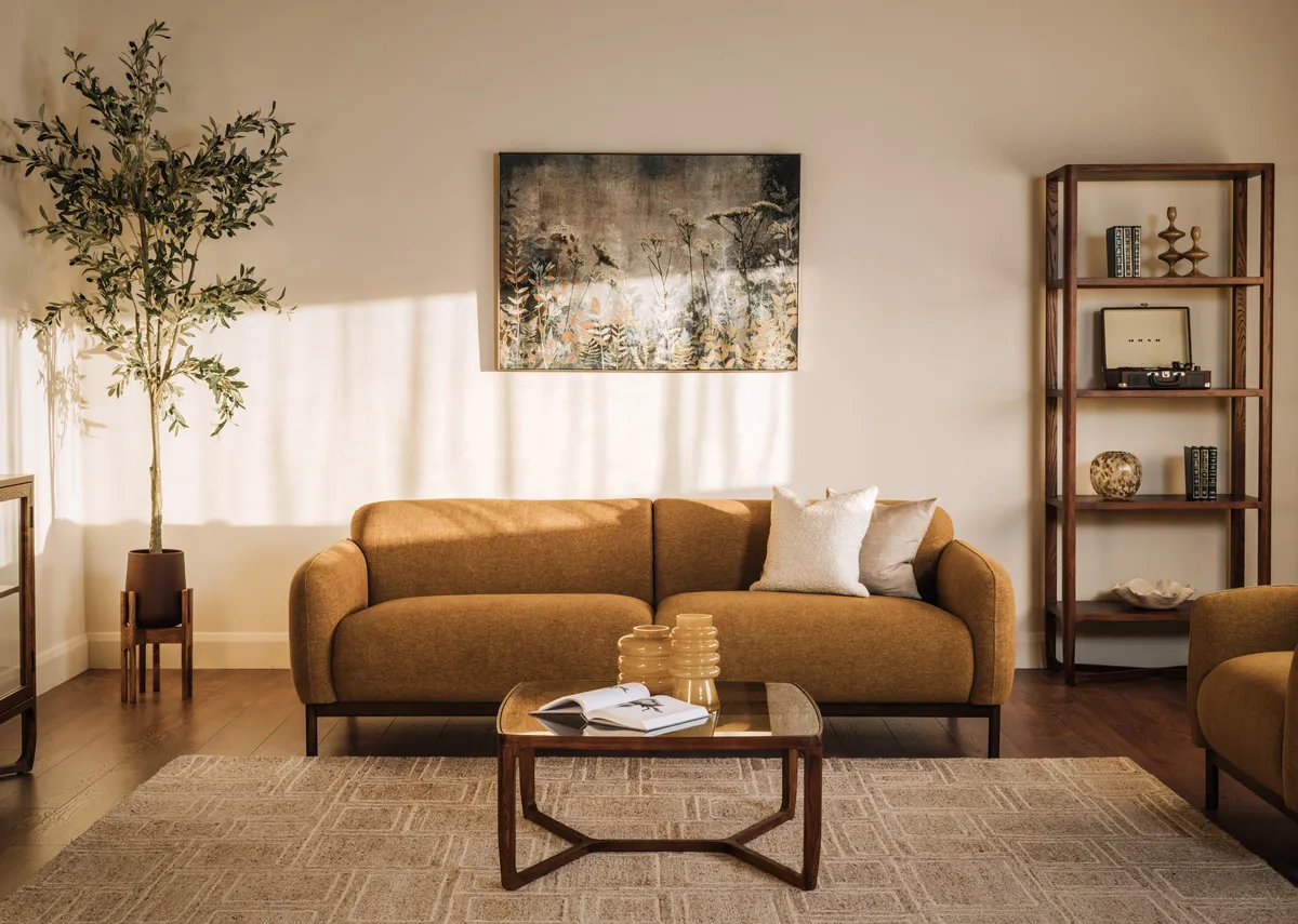 A lifetsyle image of the loft gold sofa with tearose planter and Cameo coffe etable with bookcase and Fanciful print.