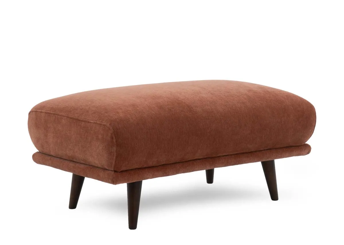 Large footstool in rust colored fabric viewed from a slight right angle.