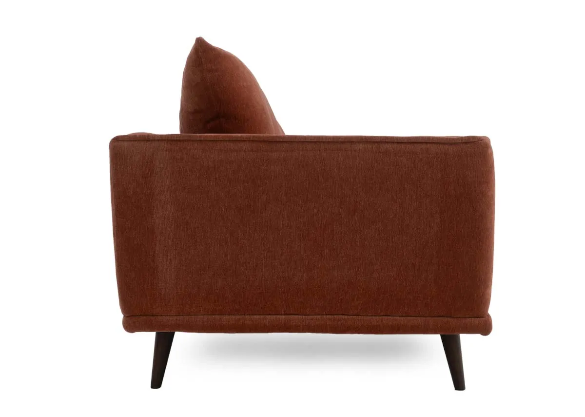 Two seater sofa in rust colored fabric showing the side profile with the armrest and flared back cushion.