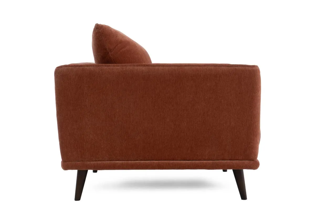 Cuddler armchair in rust colored fabric showing the side profile with the armrest and flared back cushion.