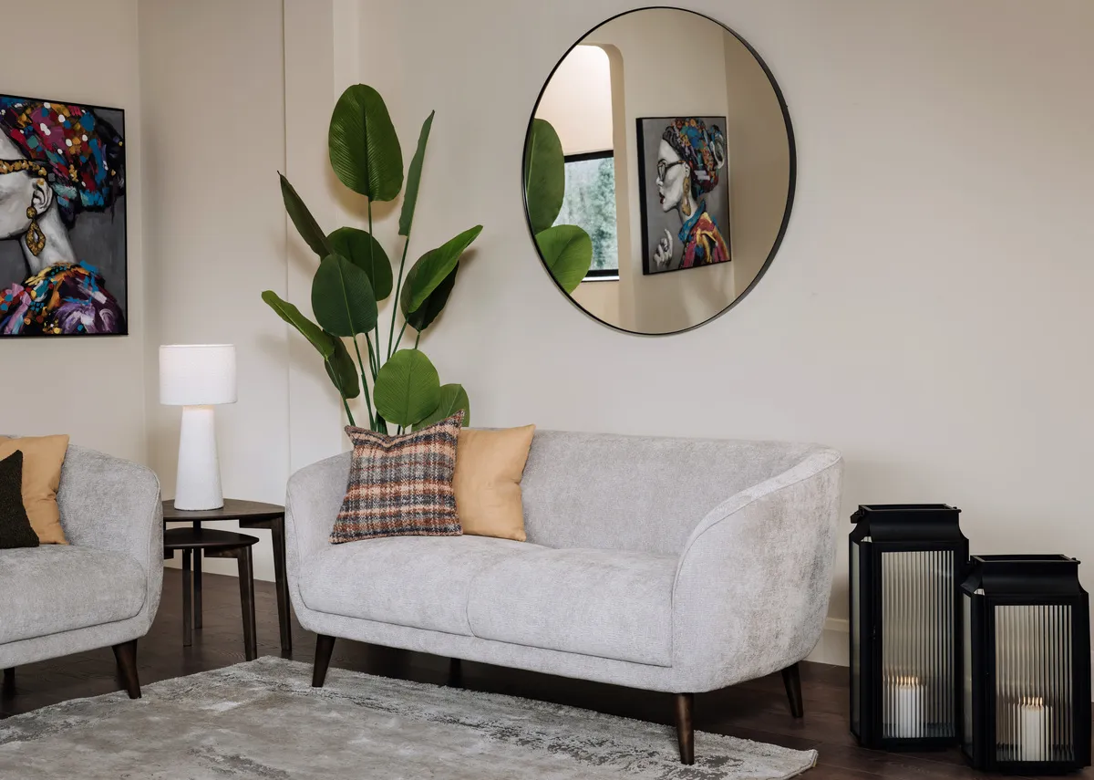 A lifestyle image of the Amber silevr 2 seater sofa with Elling mirror