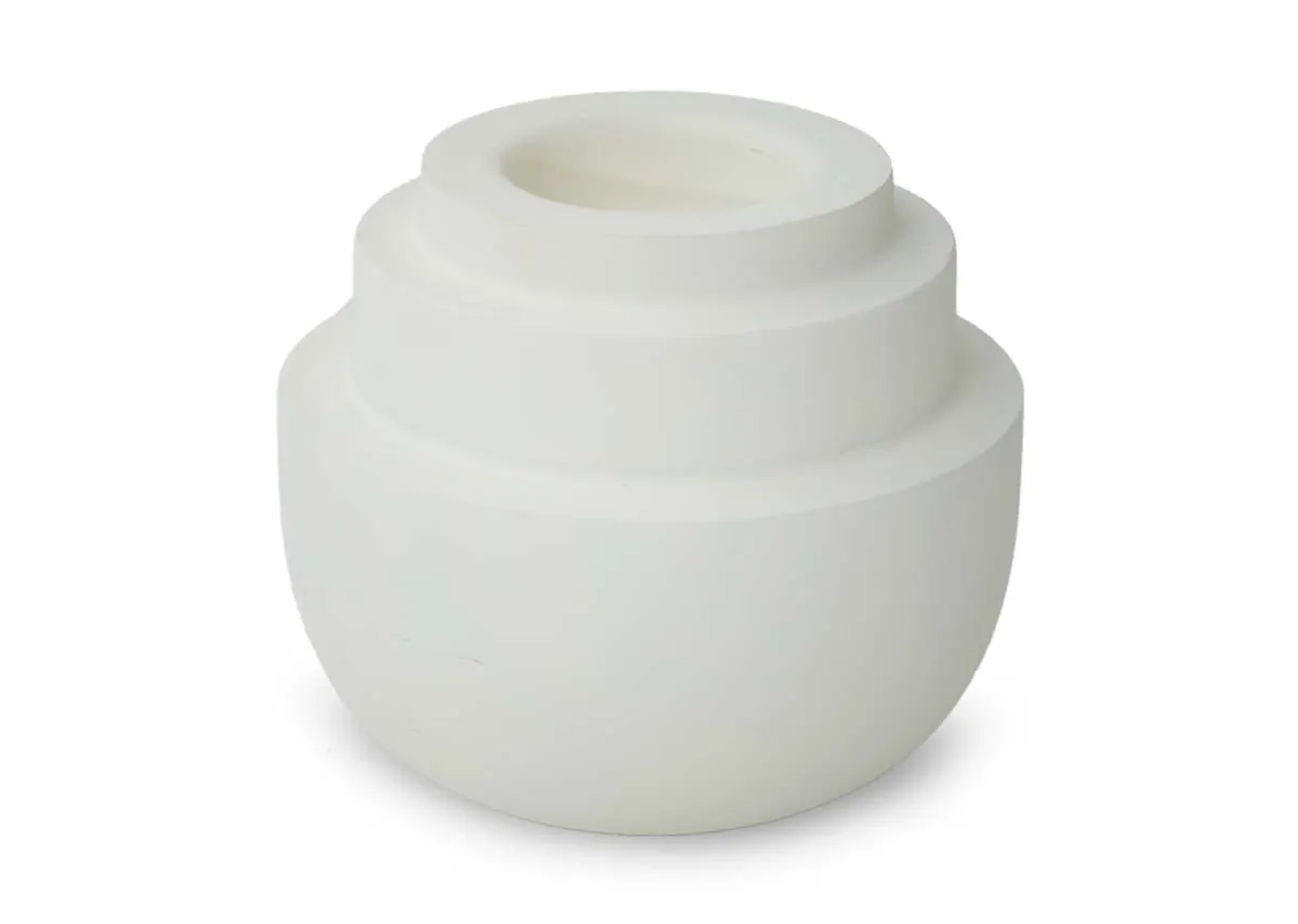 A small matt cream tealight holder with a rounded base and three concentric tiered sections on top shown at an angle.