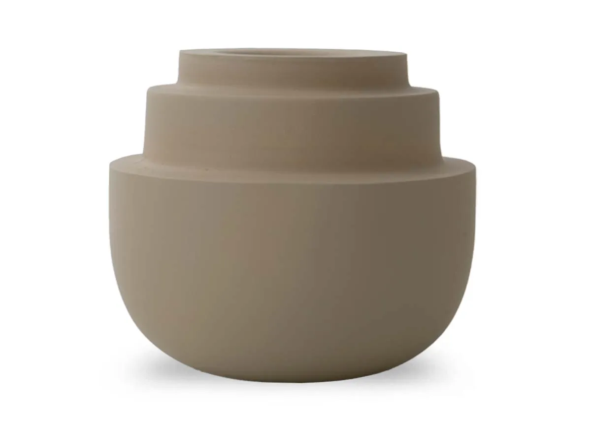 A matt sand colored tealight holder with a rounded base and three concentric tiered sections on top shown at an angle.