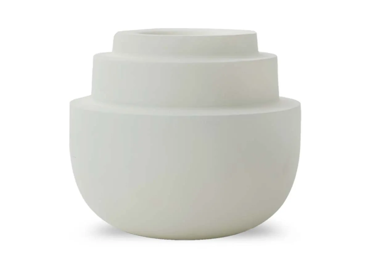 A large matt sand colored tealight holder with a rounded base and three concentric tiered sections on top shown from the front.