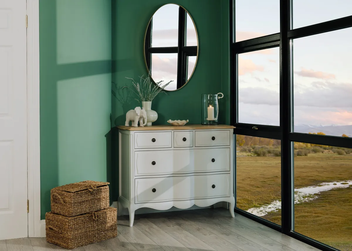A lifestyle image of the Ameliw chest of drawers with gold elling mirror and baskets