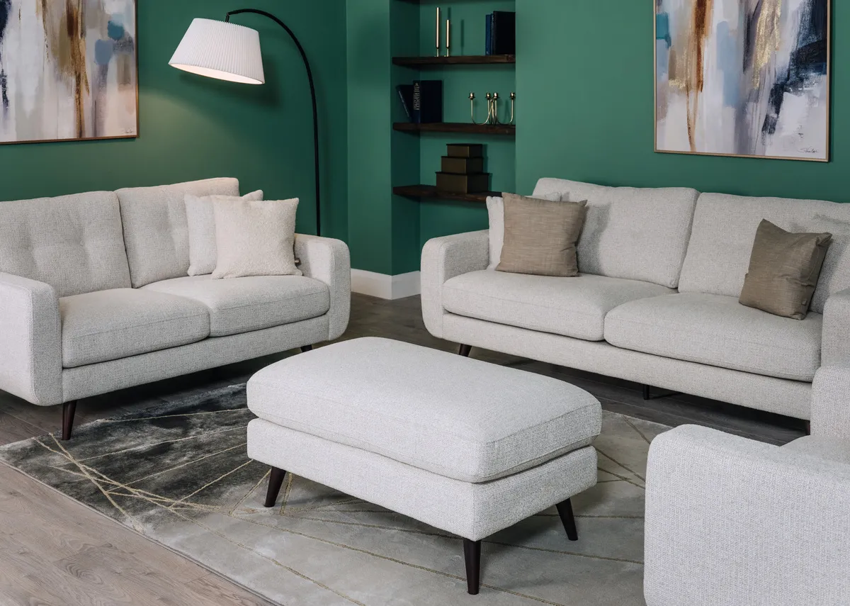 A lifestyle image of the Bandon light grey footstool with matching sofas.