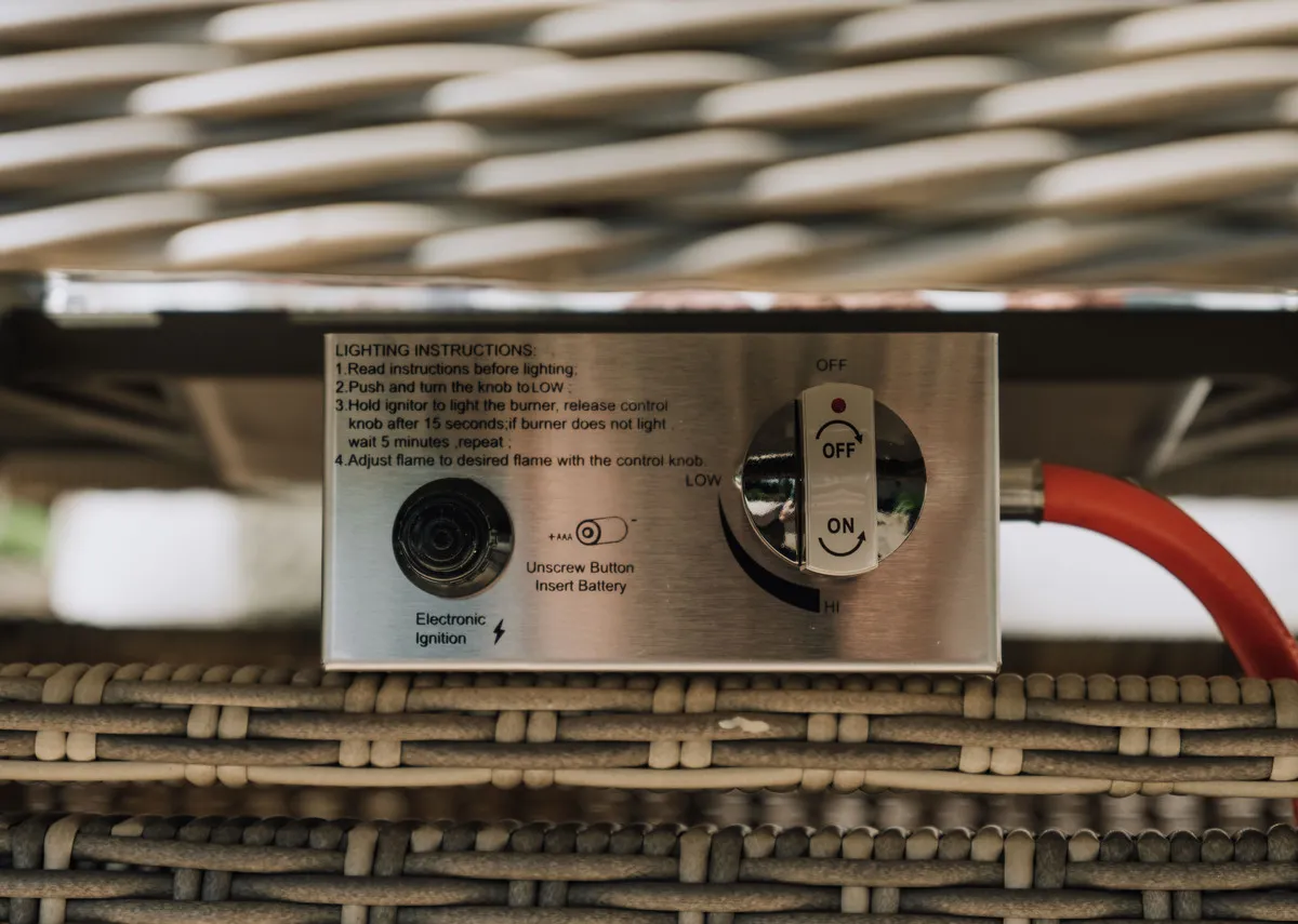 A beige corner garden sofa with 2 ottomans and a glass top rising table. Closeup of teh gas settings