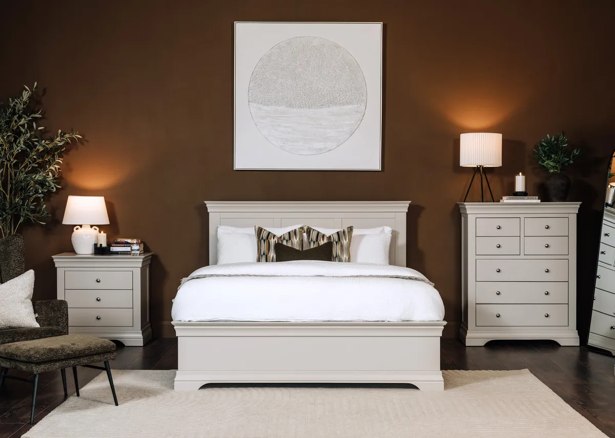 A lifestyle image of the Dove taupe bedroom range with pathways picture and Nenagh bedside lamp and Bronx chair.