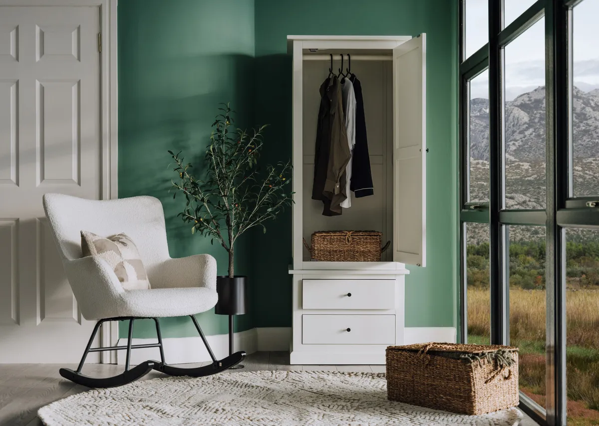 A lifestyle image of the Atlas wardrobe with door open showing space with the Percy rocking chair and basket in a window view
