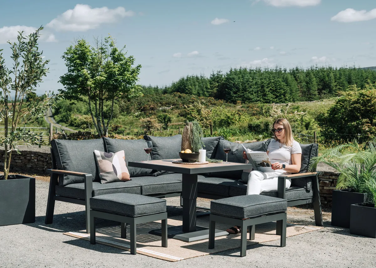 A lifetstyle of the Soho Garden set in a ba ck garden with planter and landscape and Ola reading a newspaper.