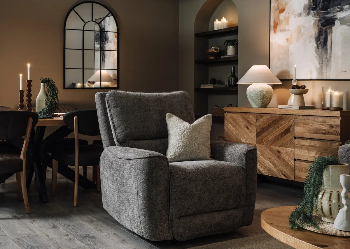A lifestyle image of the Ashbrook recliner in fixed position with the Ellipse coffee table and sideboard.