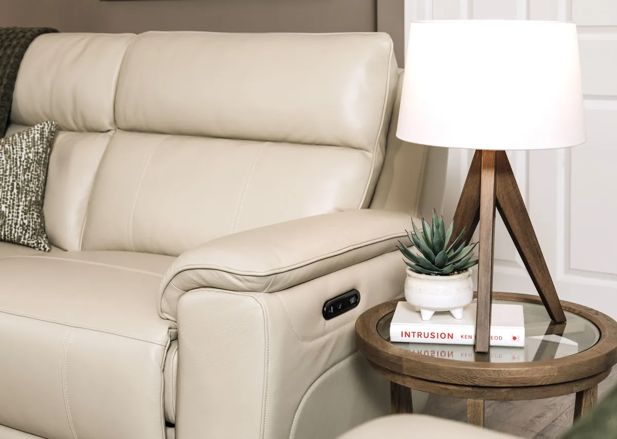 A lifetsyle image of the Aura leather 2 seater showing padded armrest with Glenveagh table lamp