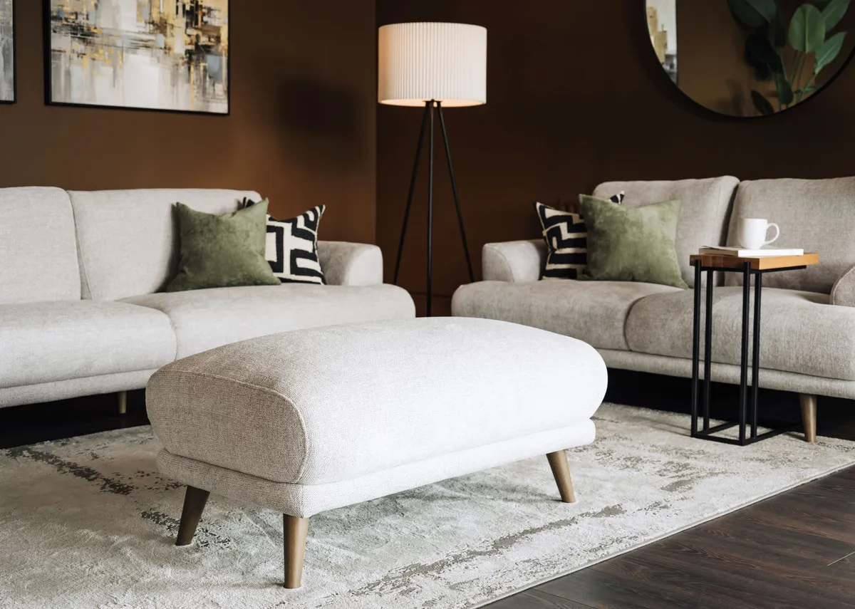 A lifestyle image of the Legend Footstool with matching corner sofa and kylo rug.