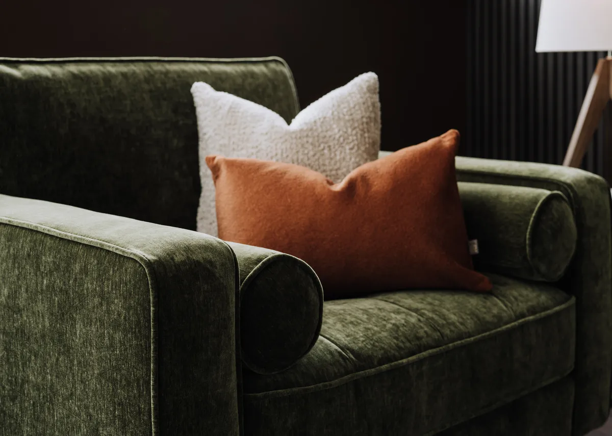 A lifestyle image of the Genoa armchair with a closeup on the walnut leg