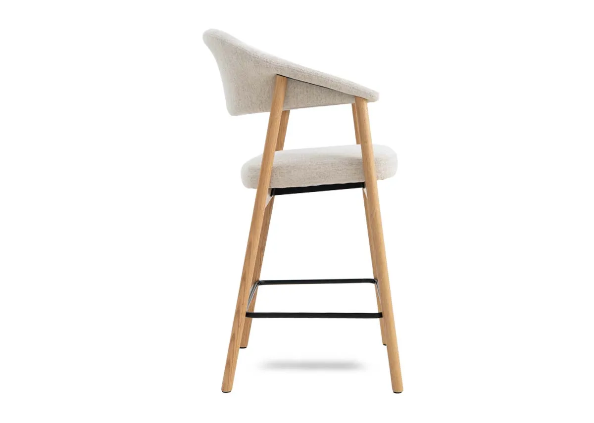 A natural oak  framed counter stool with cream fabric backrest and padded seat from EZ Livings Elk range. Side view of metal foot wrung