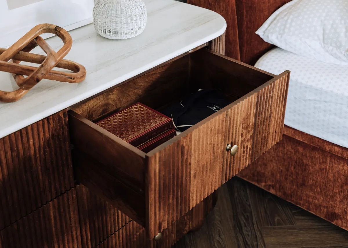A lifestyle image of the Bunton dresser with a closeup on the marble table top and top drawer open.