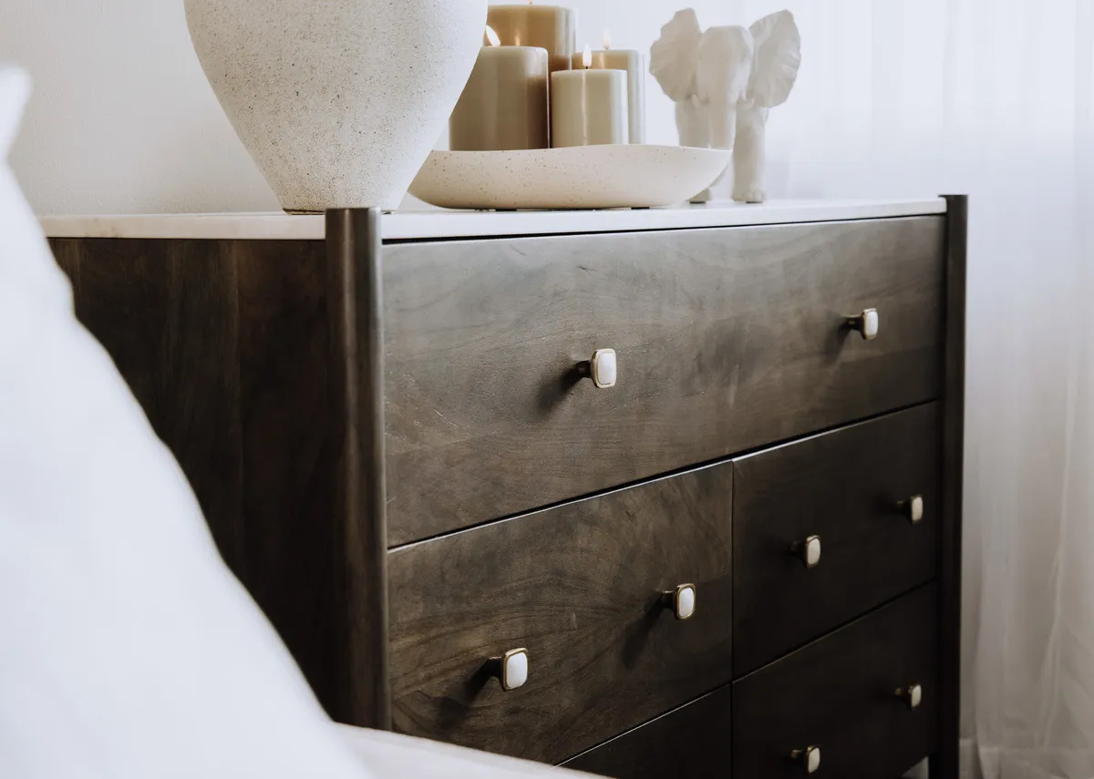 A lifestyle image of the Nora chest with a closeup on the marble finish table top with Vase and elephant ornament.