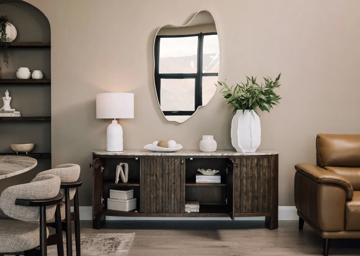 A lifestyle image of the Eden sideboard with doors open showing the storage capacity with Foyle lamp and Savoy armchair.