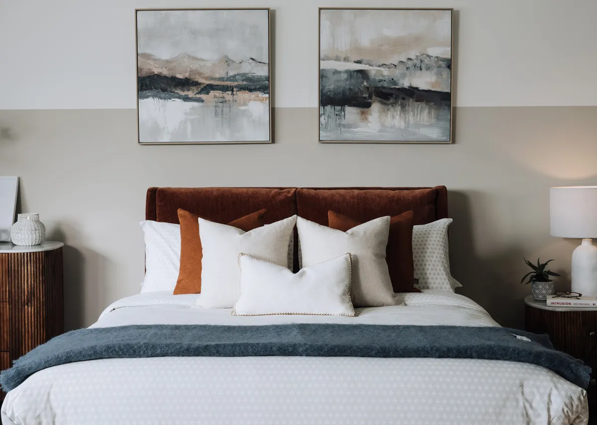 A lifestyle image of the Country clay cushion with a selection of cushions on the Comfy rust bed