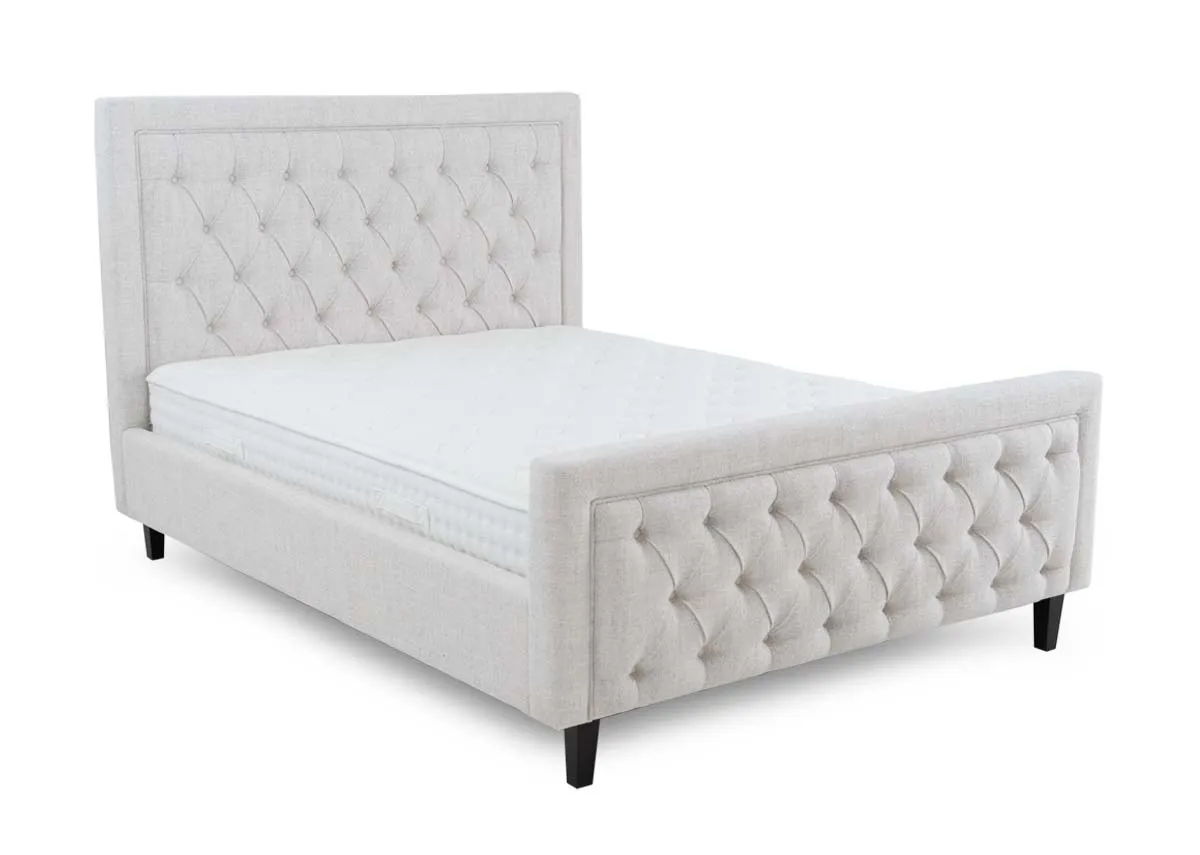 A 4ft6 double bedframe with high tufted head and footboard from EZ Livings Majestic range. Angled view.